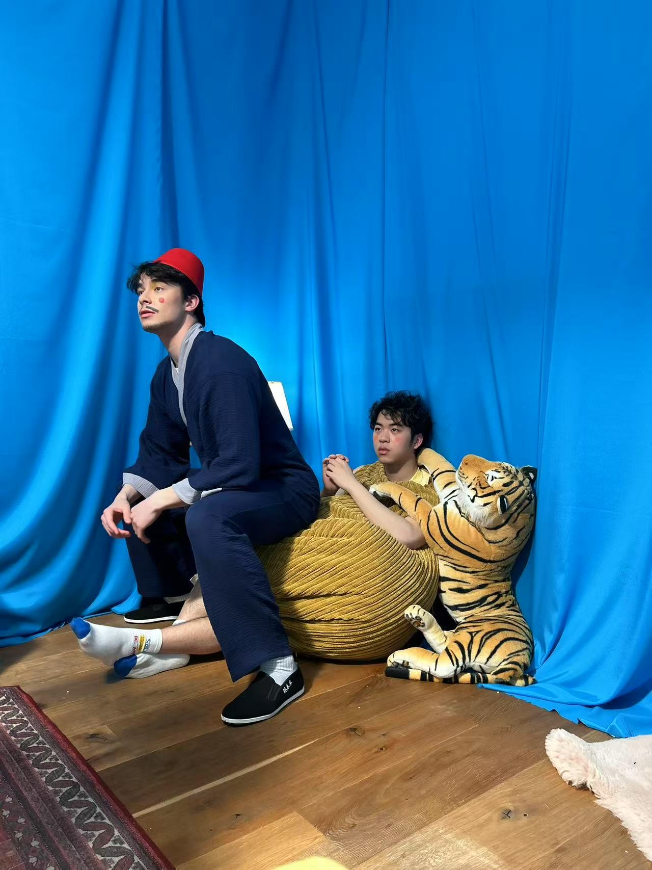 Two performers against a vivid blue backdrop with a toy tiger