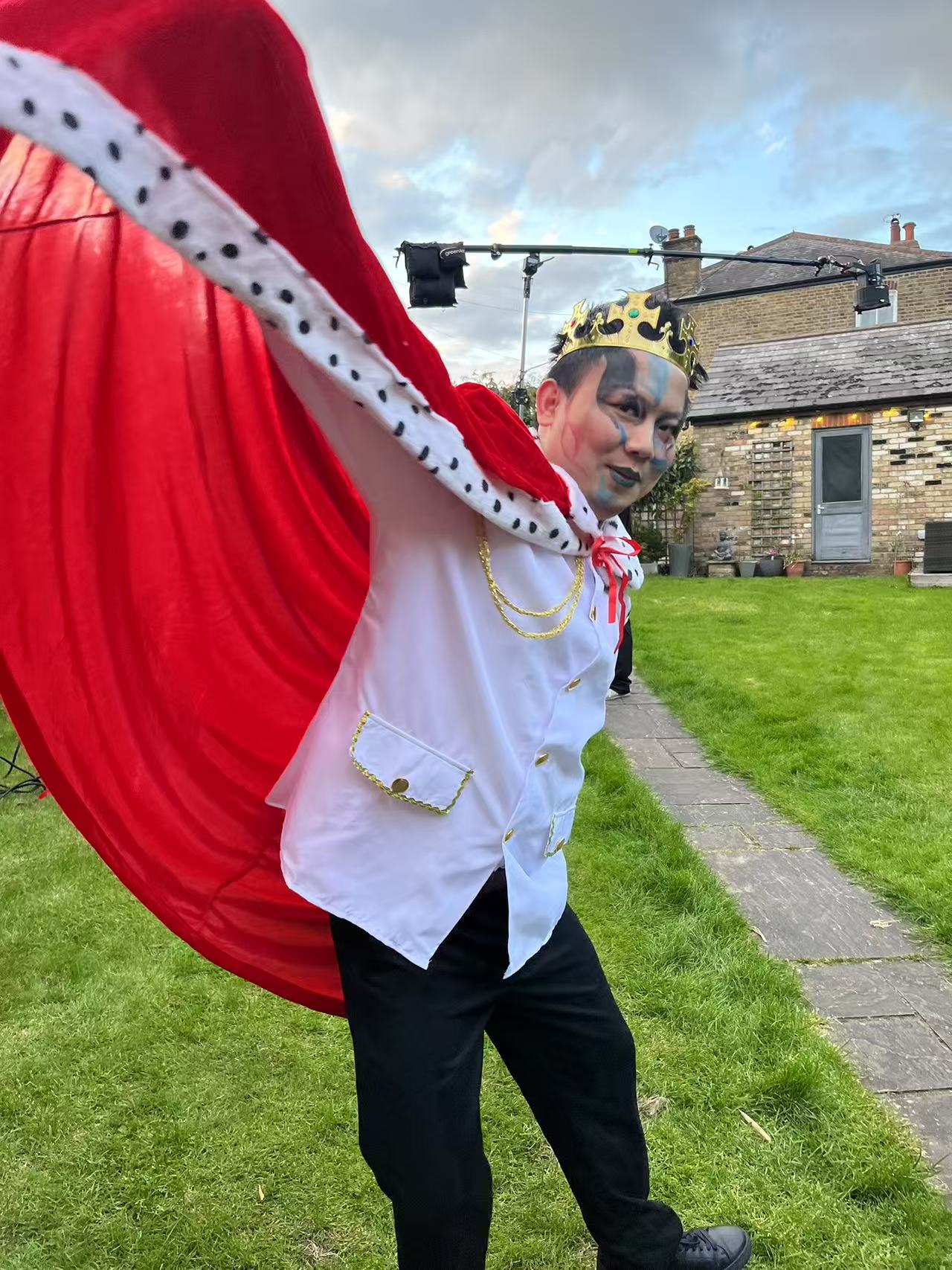 Performer in a crown and red cape on an outdoor set