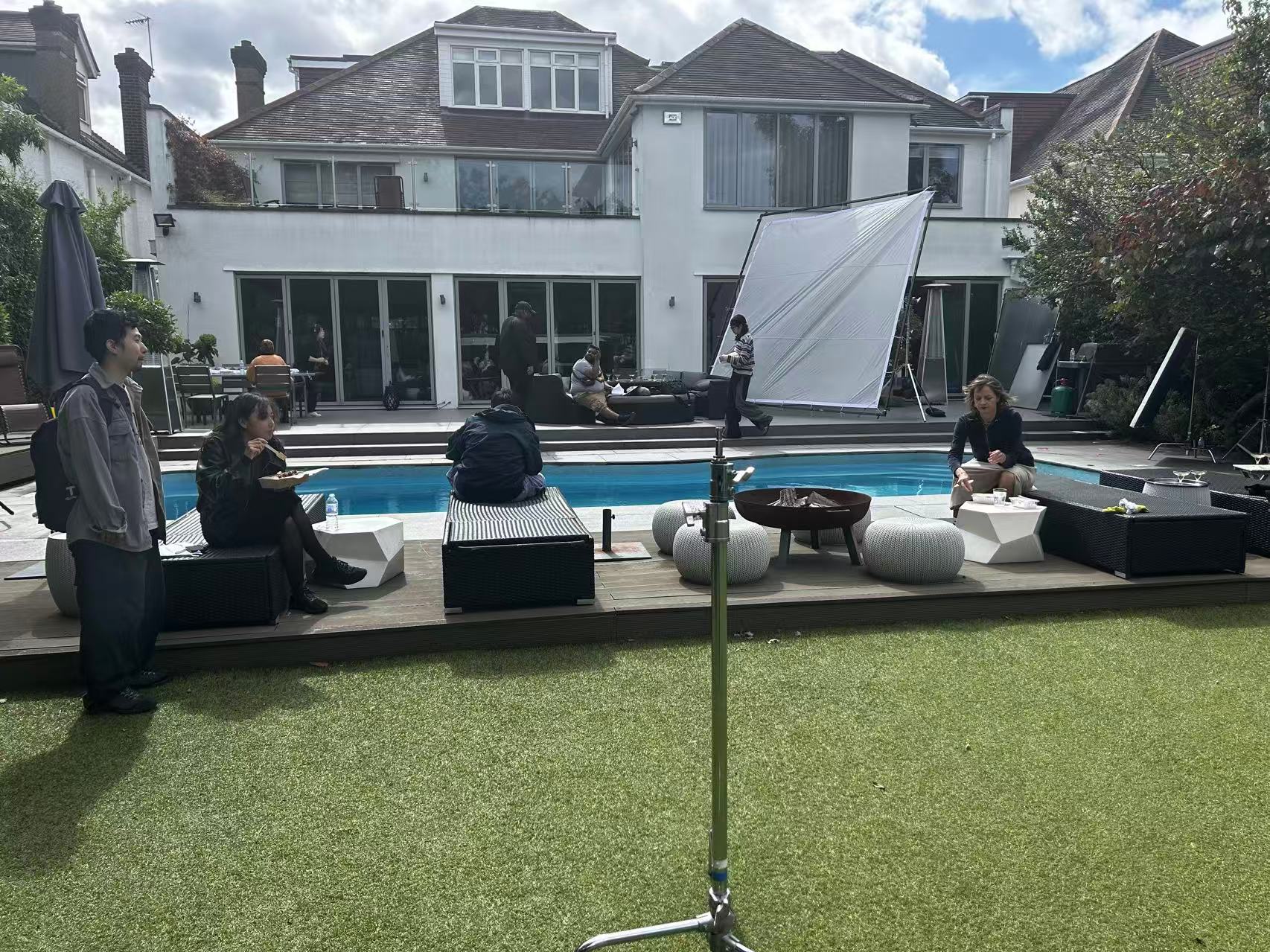Cast and crew beside a swimming pool with lighting equipment