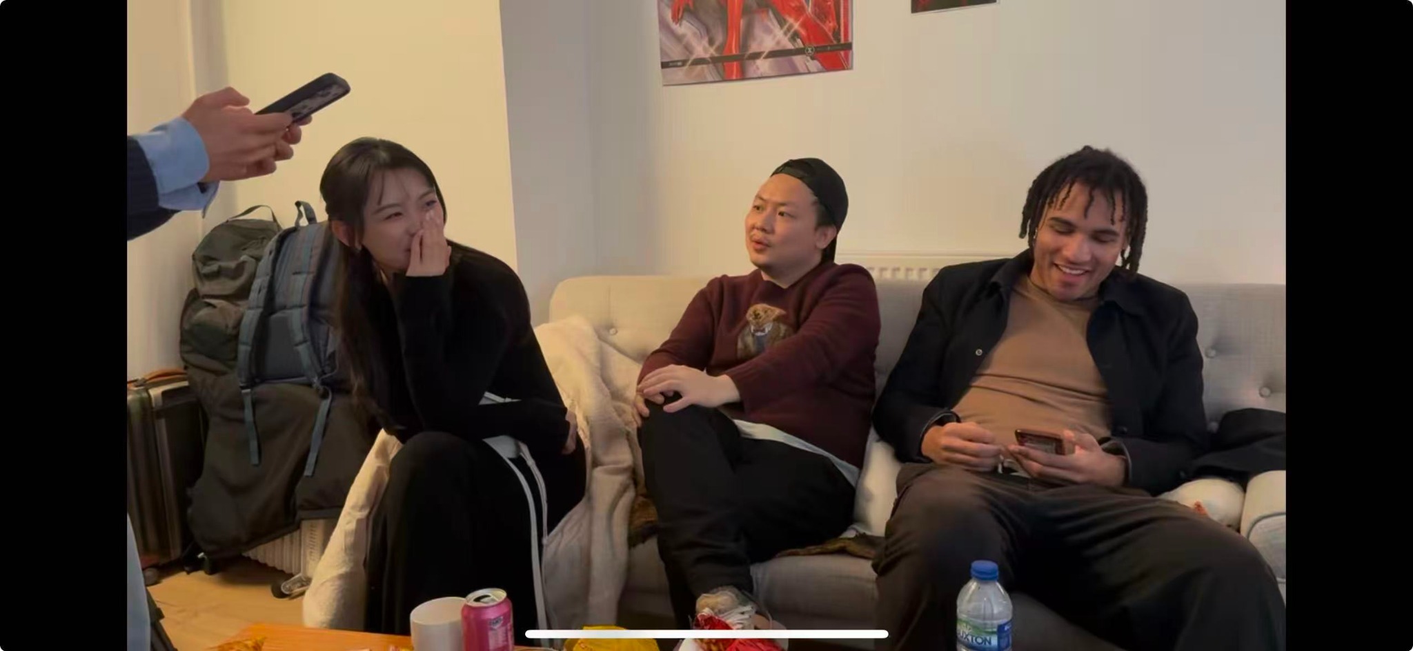 Three people seated on a sofa between takes