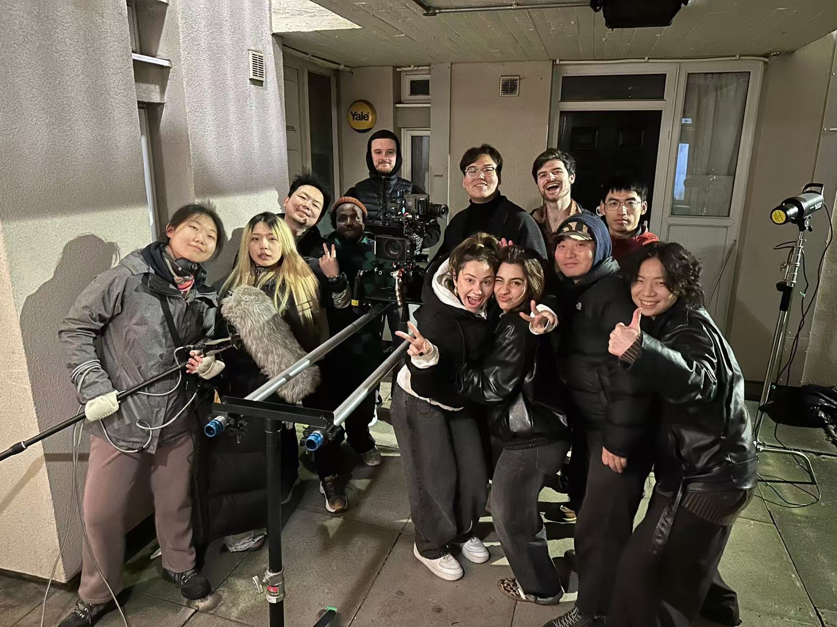 Cast and crew gathered around a camera for a group photograph